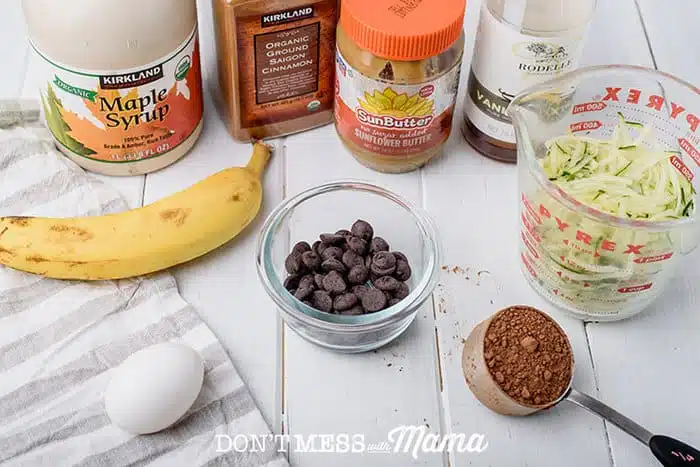 ingredients to make zucchini chocolate muffins like shredded zucchini, chocolate chips, and an egg
