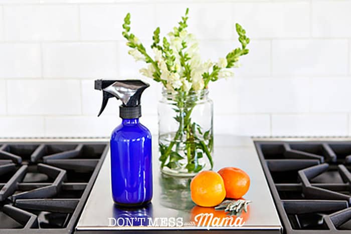 Closeup of glass cleaner with flowers and oranges on a stovetop