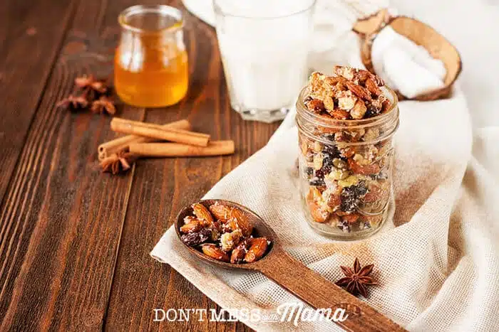 Closeup of nuts and dried fruit in a glass jar and wooden spoon