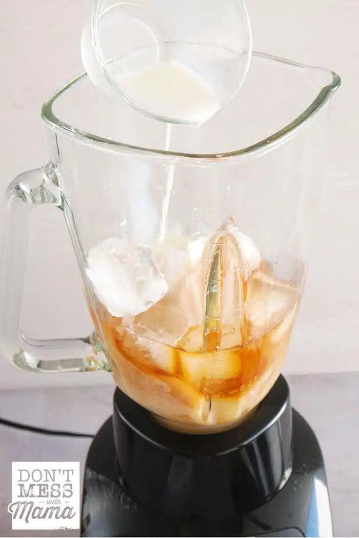 Adding milk to a blender with coffee and ice