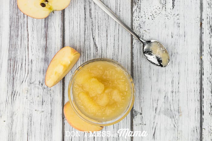 A photo of the easiest slow cooker applesauce in a small white bowl on a wooden surface