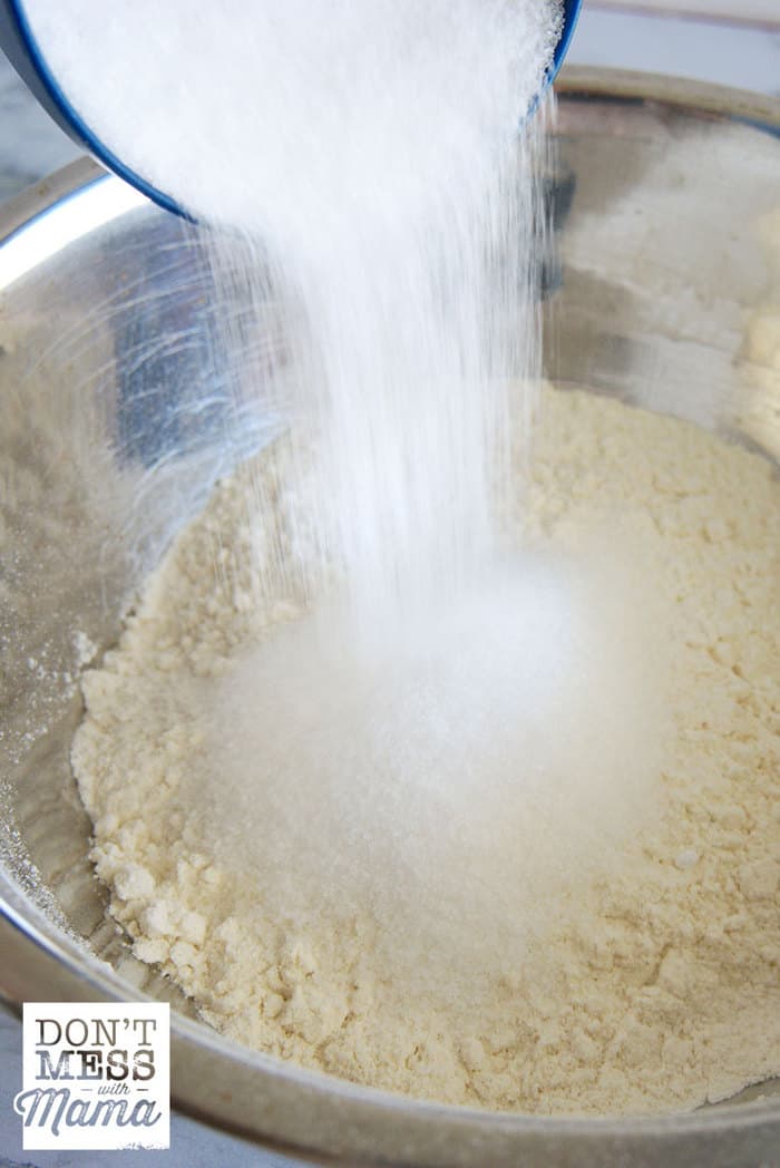 Adding salt to a mixing bowl with flour.