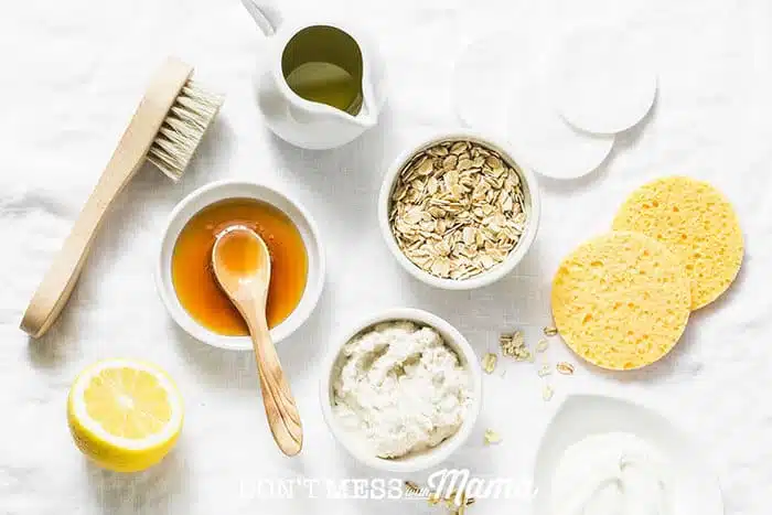 Closeup of honey, oats, cream, oil, lemon, sponges and brushes to make homemade skin care products