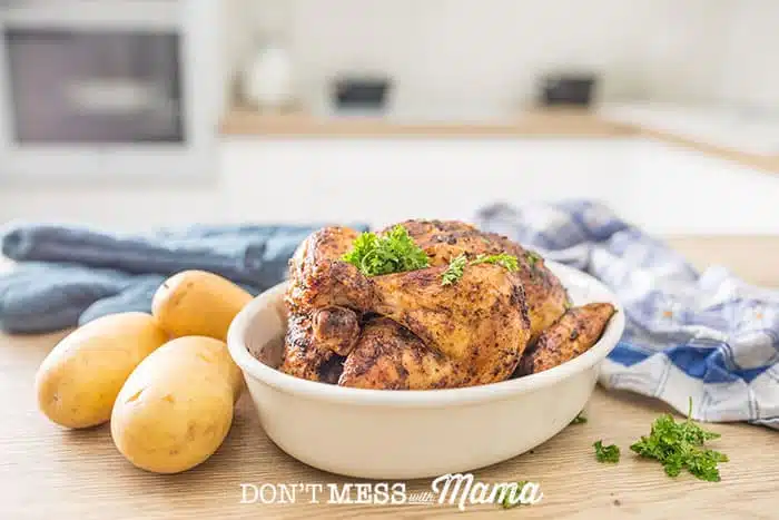 An instant Pot Roast Chicken sitting on a large serving plate garnished with thyme sprigs