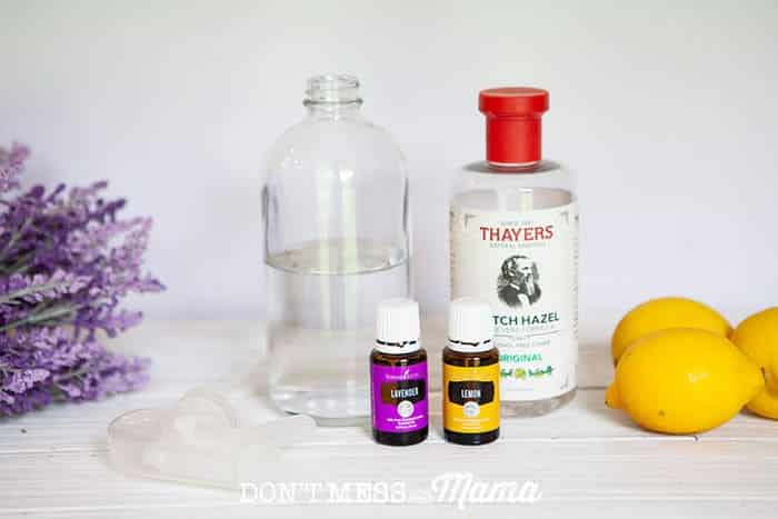 Closeup of glass spray bottle, witch hazel, lavender, lemons and essential oils