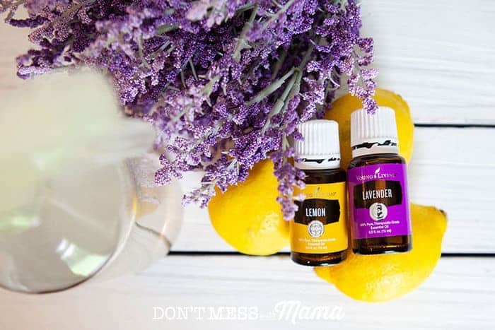 Top-view of glass spray bottle, lavender flowers, lemons and essential oils