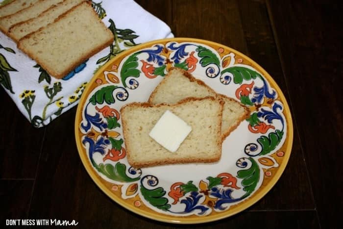 Two slices of Gluten-Free Sandwich Bread on a plate topped with butter
