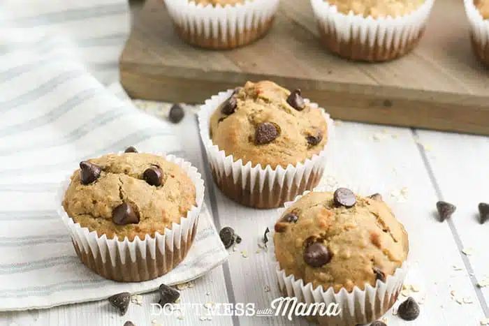 banana chocolate chip muffins on a table with chocolate chips sprinkled around them