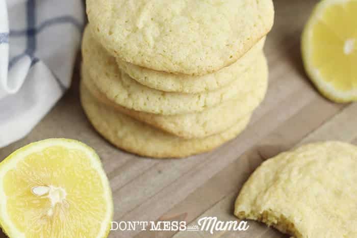 Gluten-Free Lemon Cookies piled on a cutting board with lemon slices in the background