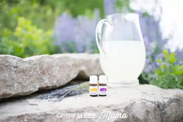 Closeup of lemon and lavender essential oils next to a pitcher of lemonade