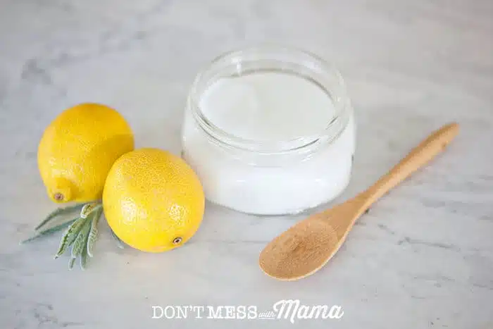 Closeup of soft scrub cleaner in a glass jar next to two lemons