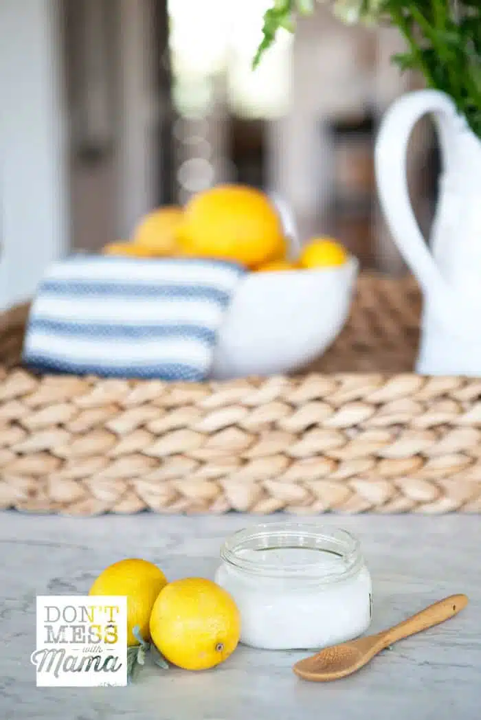 Closeup of a soft scrub cleaner in a jar next to a couple of lemons in a kitchen