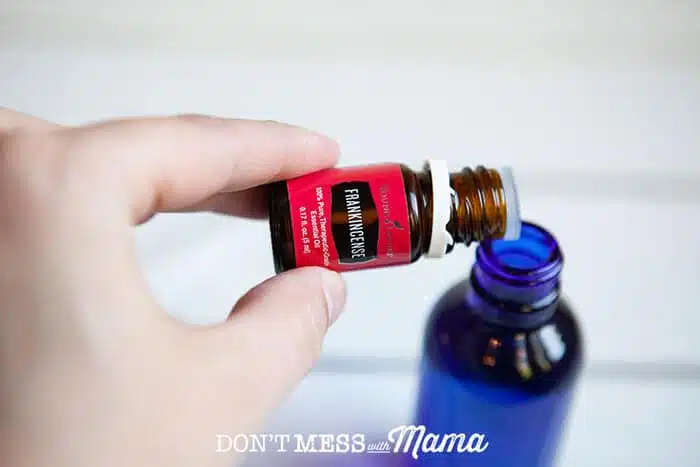 Closeup of hand adding essential oil to a bottle of DIY facial oil moisturizer