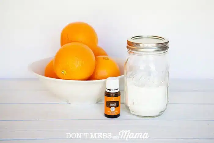 DIY Natural Carpet Freshener in glass jar next to a bowl of oranges