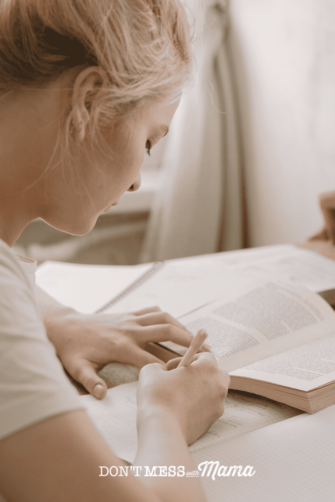 woman concentrating on book with pencil in hand