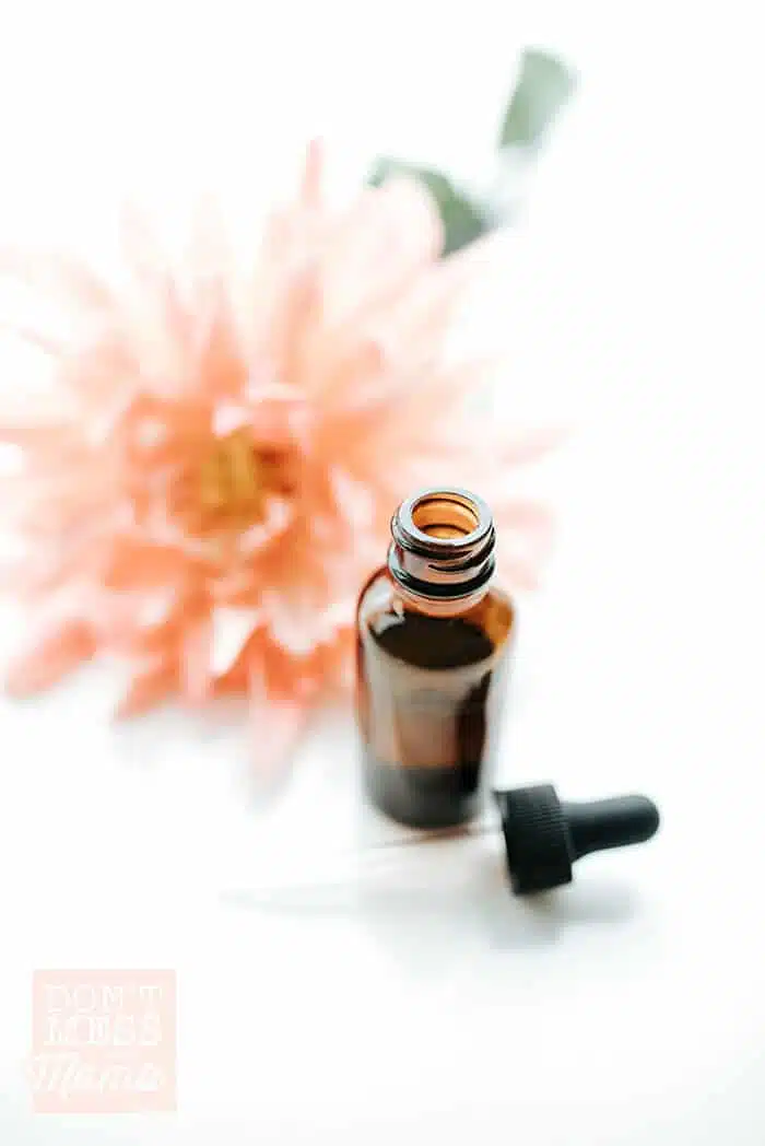 Shot of DIY argan hair oil serum in a glass bottle with a flower in the background