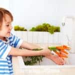 boy washing carrots in the kitchen