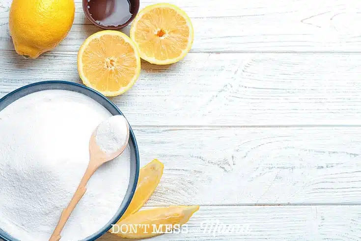 Closeup of baking soda in a bowl next to sliced lemons