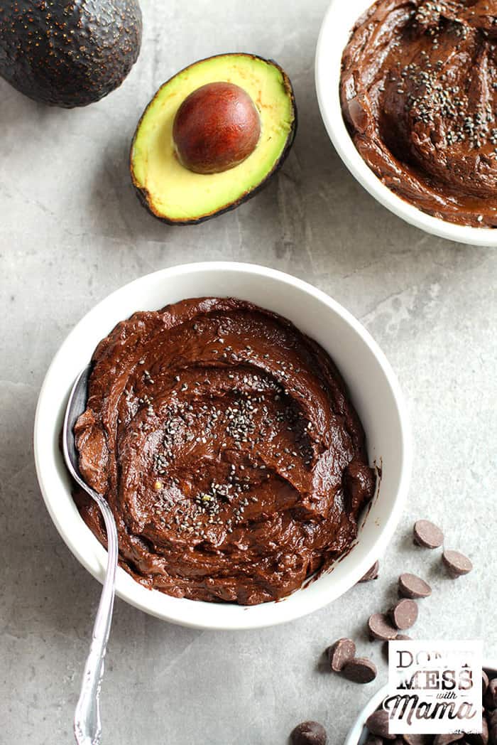 chocolate pudding in a bowl next to cut avocados