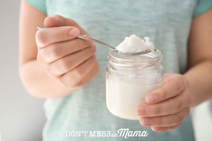hands holding a jar and spoon with coconut oil