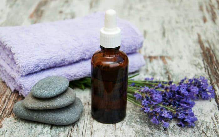 A small bottle of DIY make up remover sitting on a wooden surface next to lavender