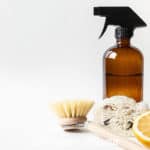 DIY Natural Pine Cleaner in a spray bottle with a brush and a half orange