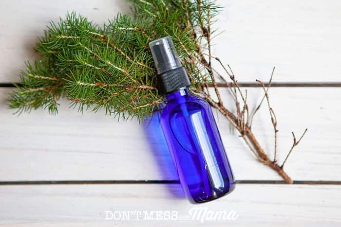 Close-up of a glass spray bottle of DIY Aftershave on a branch of pine bark