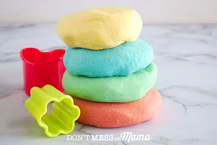 Stacked DIY Play Dough on a table with cookie cutters