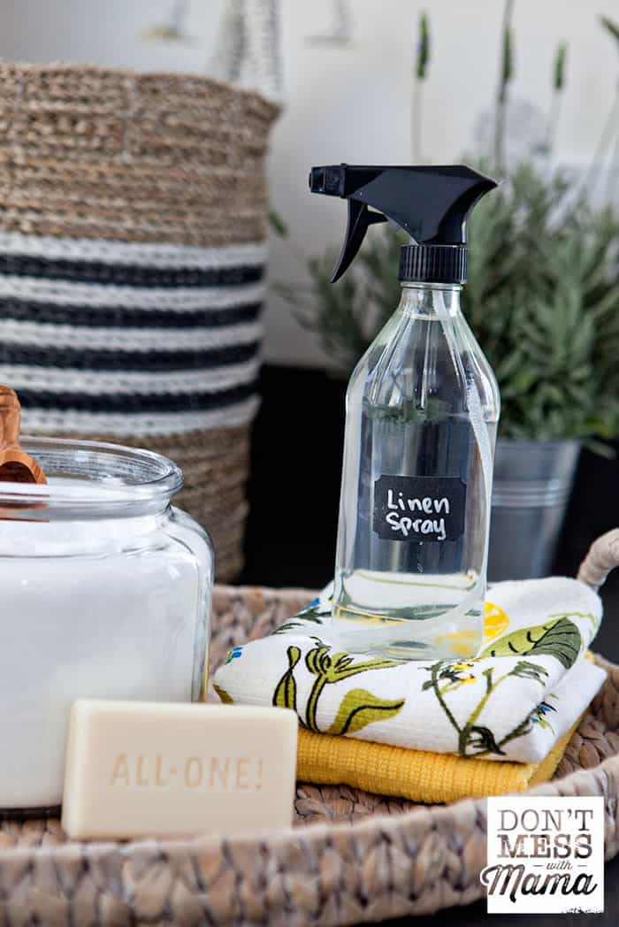 Bottle of homemade linen spray next to a bar of soap and homemade laundry detergent