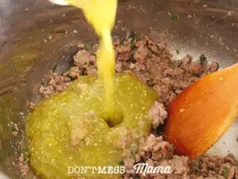 pouring salsa verde onto cooked ground beef