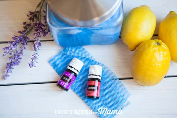 DIY Reusable Cleaning Wipes with bottles of essential oils and lemons on a table
