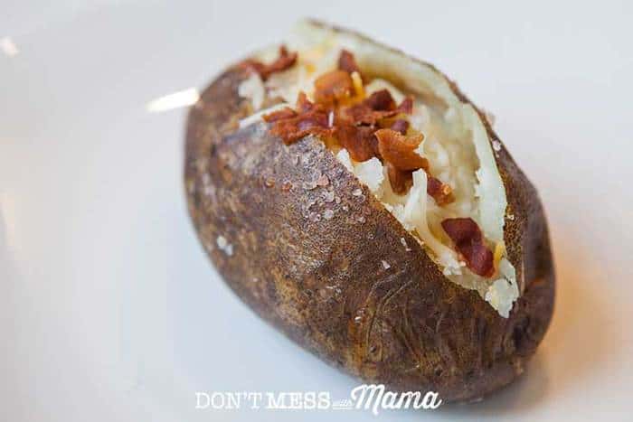 A close up of an Instant Pot Baked Potato on a white plate topped with bacon