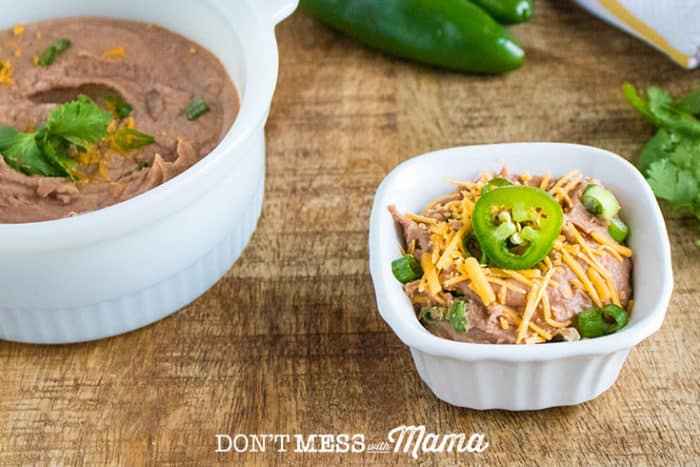 Instant Pot Refried Beans in a white dish topped with cheese