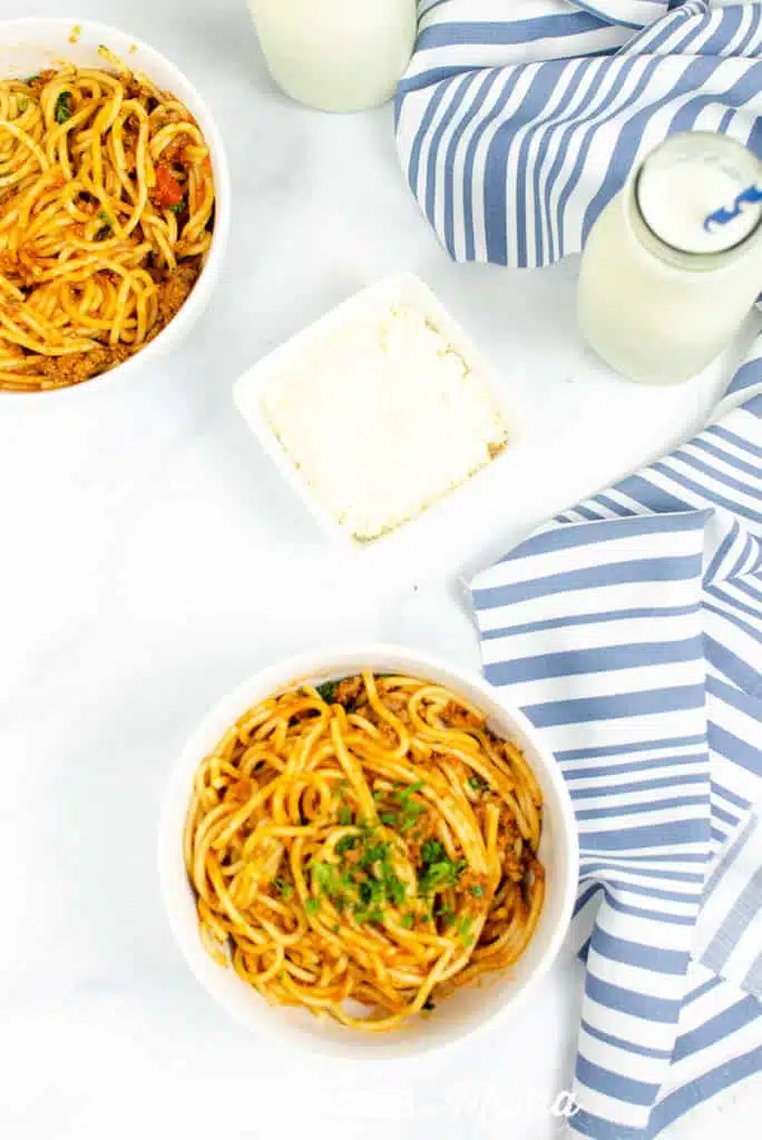 Spaghetti in a white bowls on a white countertop - part of the family friendly healthy meal plan