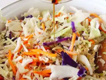adding gluten-free soy sauce to a pot with shredded cabbage and ground chicken