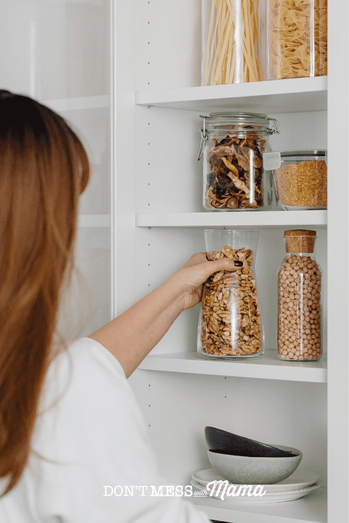 woman putting glass jar back on pantry shelf
