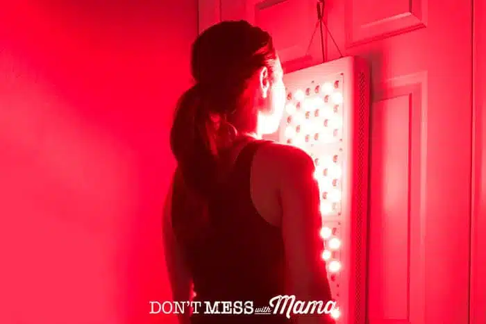 woman standing in front of a red light therapy unit