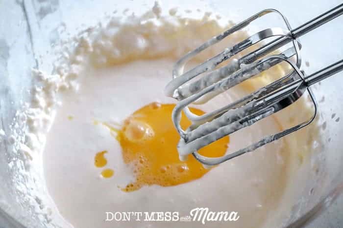 adding eggs to a mixing bowl