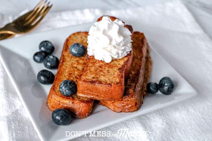 Keto French Toast on a white plate with blueberries and whipped cream 