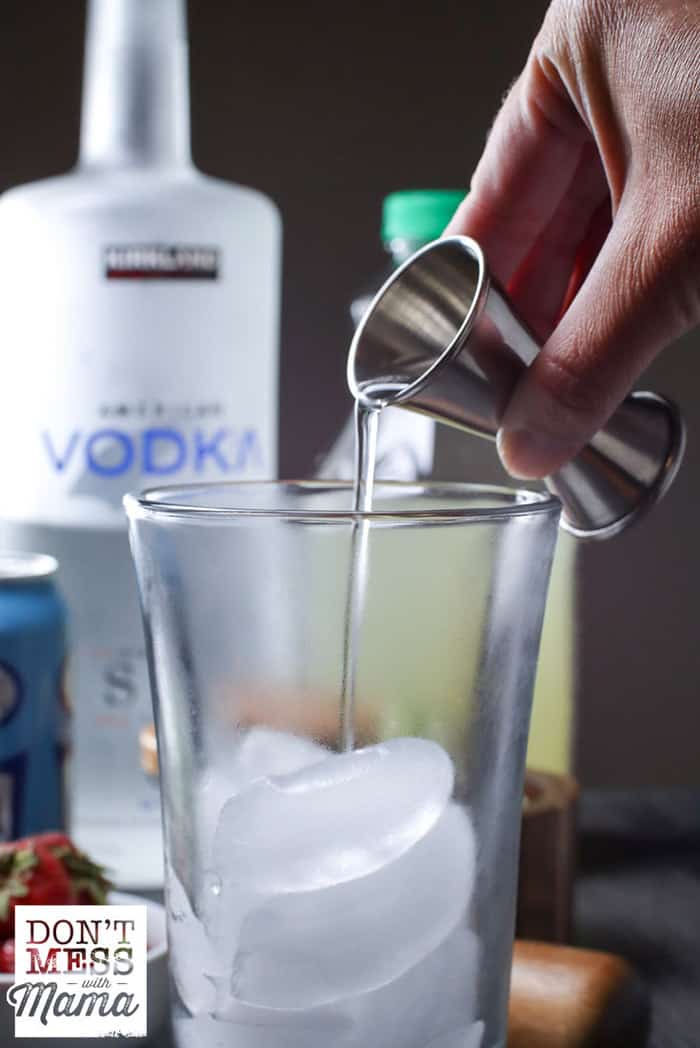 pouring vodka into a tall glass with ice
