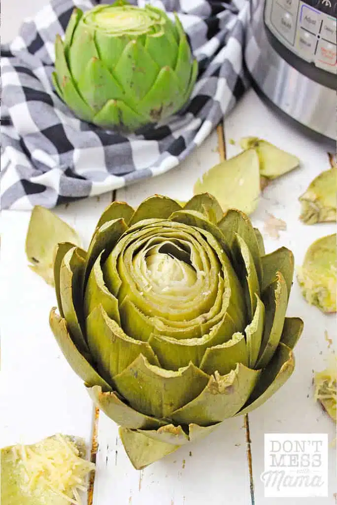 cooked artichoke on a table next to an Instant Pot