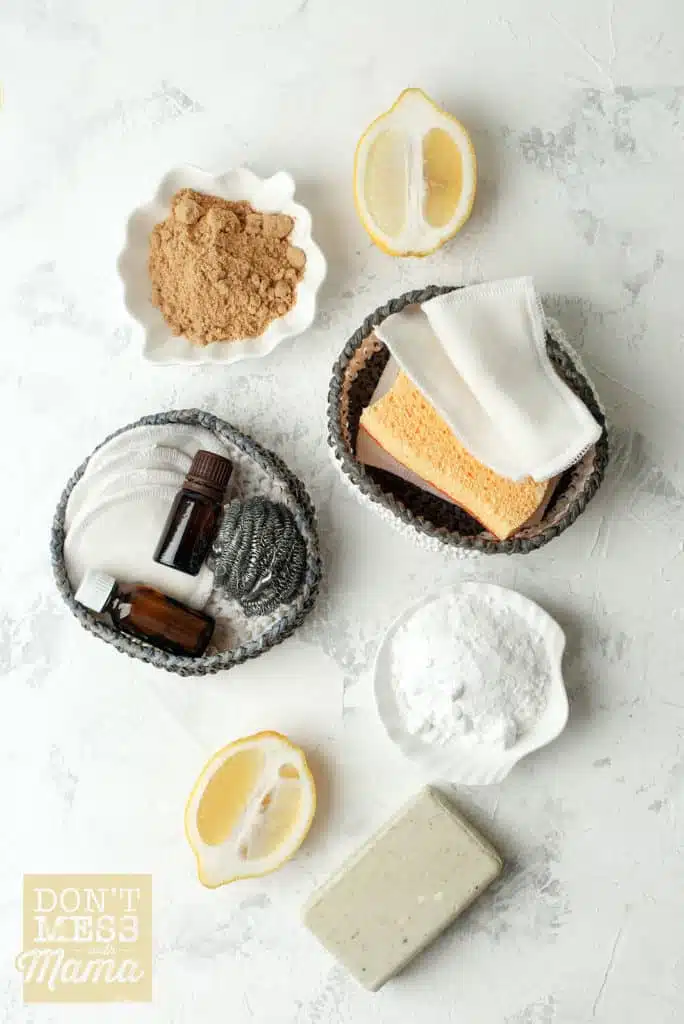 natural cleaning supplies like lemon, baking soda, sponges and essential oils on a table