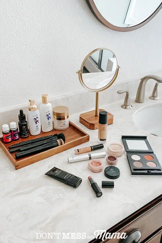 Savvy Minerals makeup liquid foundation bottles, makeup primer bottle mascara, and foundation powder on a bathroom counter
