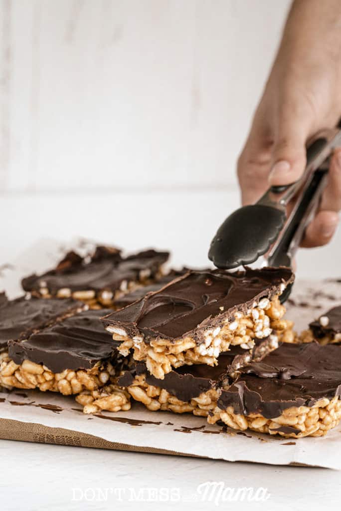 Stack of puffed rice bars with chocolate with tongs
