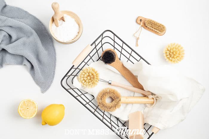 flatlay of black wire basket with natural cleaning products, lemon and cloth