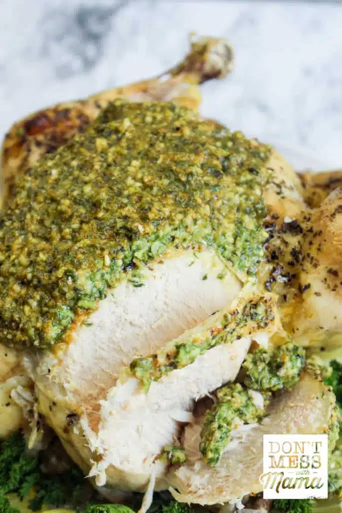 close up of cooked chicken covered in pesto