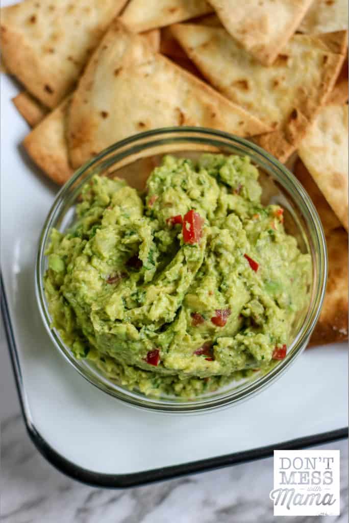small bowl of guacamole with tortilla chips on a plate
