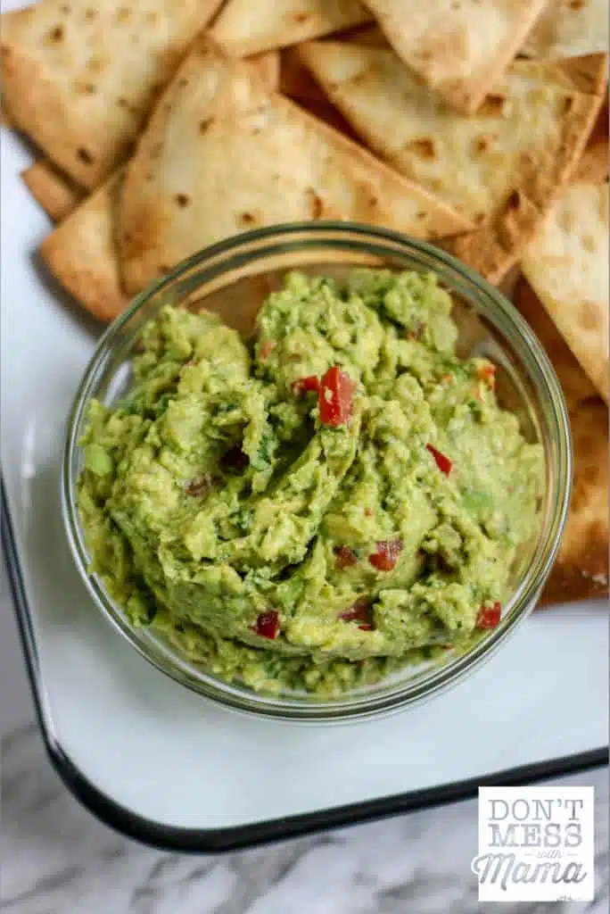 small bowl of guacamole with tortilla chips on a plate