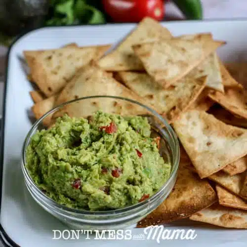 small bowl of homemade guacamole with tortillas on a plate