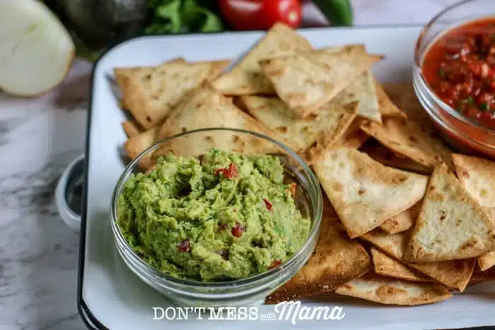 small bowl of homemade guacamole with tortillas on a plate